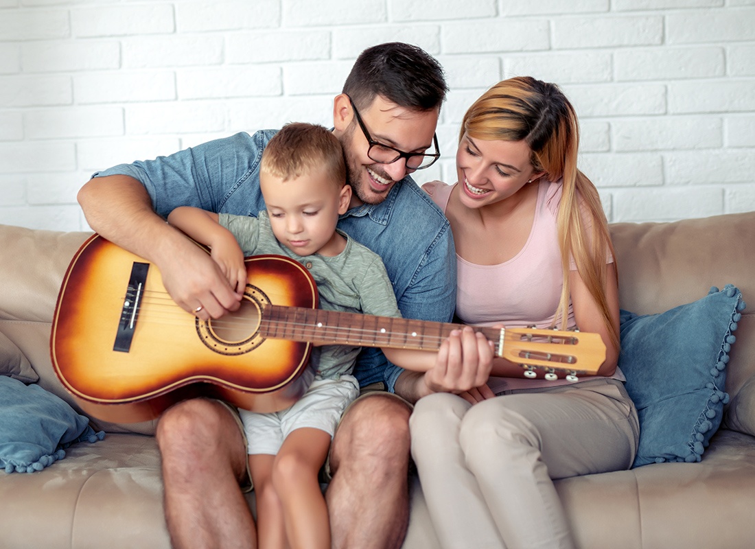 Personal Insurance - Happy Family Sit Together at the Father Shows His Son How to Play a Guitar